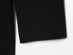 Detailed close-up of high-quality black fabric texture and neat stitching on dress sleeve