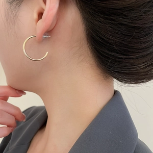 Minimalist gold C-shaped hoop earring with smooth metallic finish on model