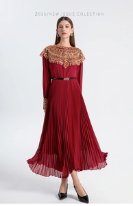 Close-up of intricate gold beadwork and sequins on the collar of a dark red pleated gown
