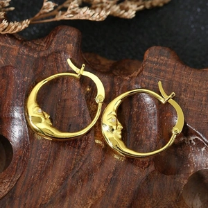 Chic gold crescent moon face earrings with embossed detail on vintage wood