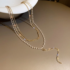 Elegant gold multi-layer necklace featuring white pearls and sparkling rhinestone tassels