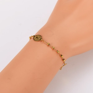 Golden stainless steel beaded bracelet with religious coin pendant on a model wrist