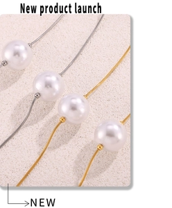 Détail de pendentifs en perles blanches sur des chaînes serpent dorées et argentées