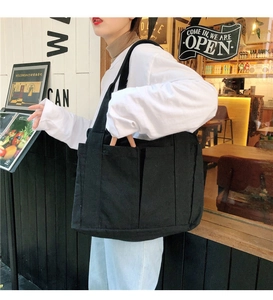 Gros plan sur un sac fourre-tout en toile noire avec deux poches frontales et bandoulières