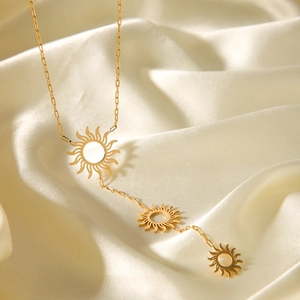 Golden stainless steel sun pendant Y-necklace with tassels on white silk background