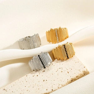 Close-up of geometric textured rings with fine stone settings on silk and stone