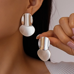 Metallic geometric oval drop earrings with brushed silver texture on a model