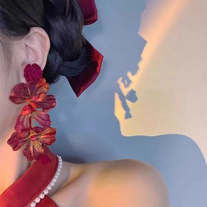 Close-up of elegant red layered fabric flower drop earrings worn by a model