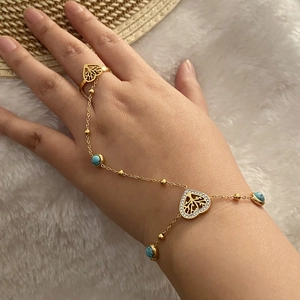 Détail de bracelet bague doré avec perles turquoise et pendentif arbre en cœur sur modèle