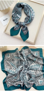 Close-up of paisley pattern on green and white silk-like neck scarf with luxury details