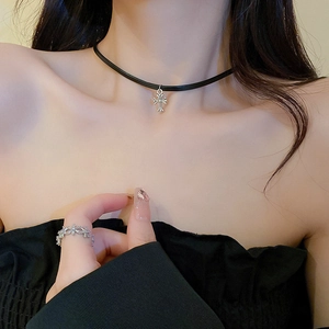 Detail view of a black faux leather choker and matching ring with silver cross pendants