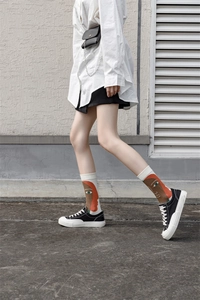 Street style view of mid-calf socks with artistic portrait patterns on a white base