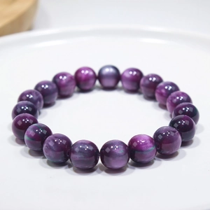 Macro shot of 8-10mm purple cat's eye stone beaded bracelet on white ceramic tray