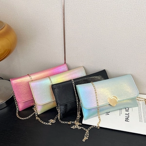 Gradient laser heart-shaped chain bags in pink, white, black and blue set on wood table