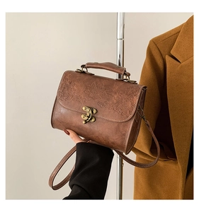 Gros plan sur un sac carré vintage marron foncé avec gaufrage floral et fermoir en métal