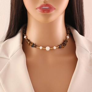 Detail of handmade stone and pearl necklace worn on a mannequin with a beige blazer