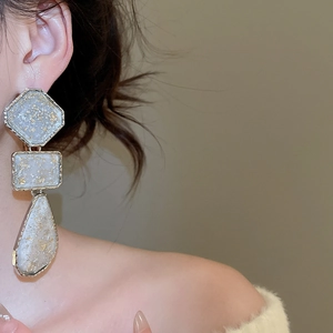 Detail of vintage geometric resin drop earrings with gold foil on a female model