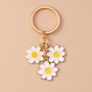 Detailed view of golden keychain featuring three white daisy flower charms with yellow centers
