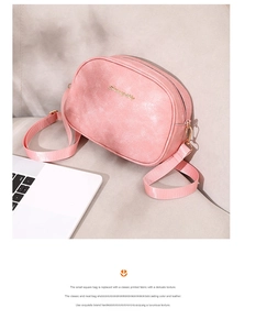 Detailed macro view of pink oil wax leather crossbody bag with golden logo on textured fabric