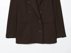 Detail of dark brown double-breasted blazer with shoulder pads and textured flap pockets