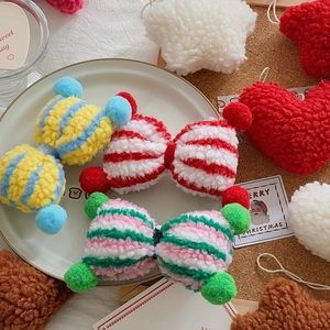 Detailed view of striped plush Christmas bow pendants with small colorful pom-poms