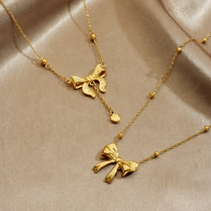 Collier doré avec pendentifs nœud et cœur sur fond élégant en satin de champagne