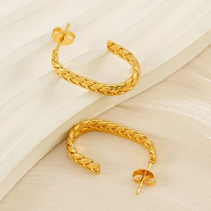 Macro detail of 18K gold plated U-shaped earrings with woven texture on silk fabric