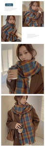 Detail view of thick orange and blue plaid scarf with soft fringe and warm knit texture