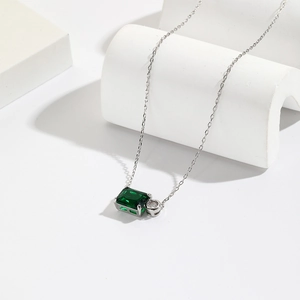 Detail of silver necklace featuring an emerald rectangular pendant and round crystal
