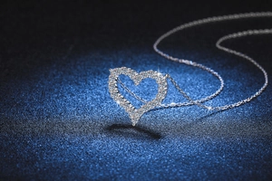 Macro shot of silver heart-shaped moissanite pendant featuring sparkling pavé diamonds