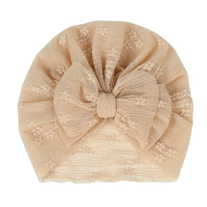 Breathable lace baby turban hat in soft pink with a large decorative floral bow