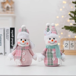 Detail of plush snowman dolls in pink and mint green plaid outfits with festive decor
