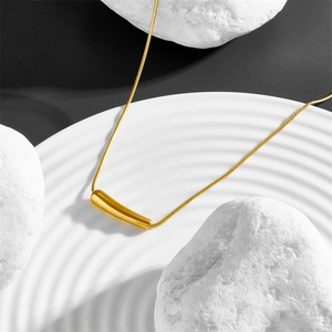 Collier minimaliste à pendentif goutte dorée sur une chaîne serpent fine et plateau blanc