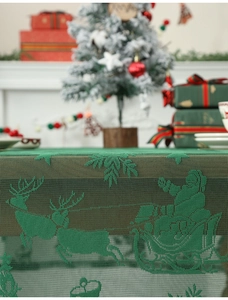 Close-up of green lace Christmas tablecloth featuring Santa Claus and reindeer patterns