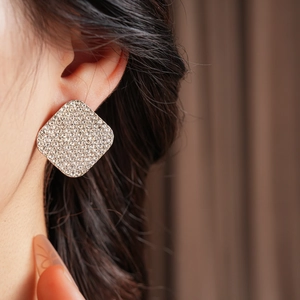 Macro view of a large silver diamond stud earring with sparkling crystals on a female model