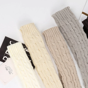 Detail shot of cable knit arm warmers in cream, beige, oatmeal, and grey shades