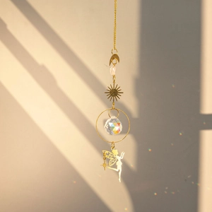 Close-up of brass fairy suncatcher with crystal ball reflecting rainbow light on wall