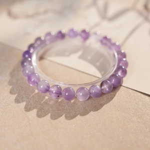 Detailaufnahme eines Amethyst-Perlenarmbands mit natürlichen Texturen auf beigem Grund