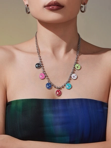 Detail of beaded necklace with colorful enamel celestial pendants and silver hoop earrings