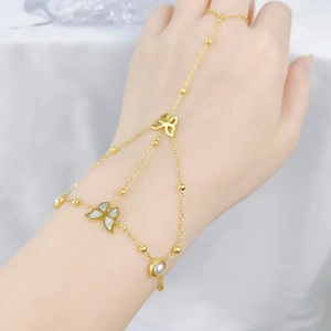 Detailed view of a gold hand chain featuring a white butterfly and pearl decoration