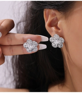 Detailed close-up of a silver flower stud earring featuring a delicate center pearl accent