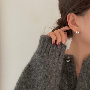 Close-up of minimalist sterling silver ball earrings worn by model in cozy knit sweater