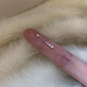 Close-up detail of a silver drop earring with gradient zircons on a soft fabric backdrop