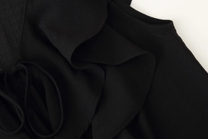 Close-up of black layered ruffle fabric with drawstring detail and woven texture