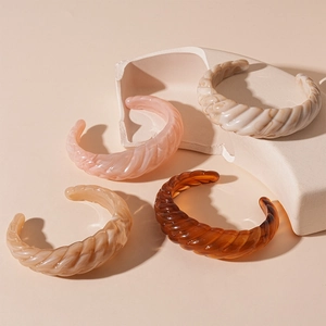 Detailed macro view of retro acrylic croissant bangles with marble and amber textures