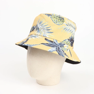 Detail of yellow cotton bucket hat with tropical blue palm leaves and pineapple print