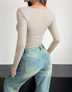 Rear view of a tight Y2K square neck long sleeve top in beige with blue denim jeans