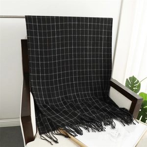 Macro detail of black and white plaid scarf with fringe on a wooden chair