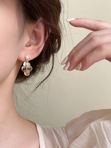 Vue détaillée des boucles d'oreilles en résine avec perles blanches et aiguilles dorées