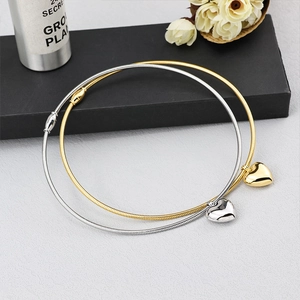 Detail of gold and silver heart pendant necklaces with sleek snake chains on a grey surface
